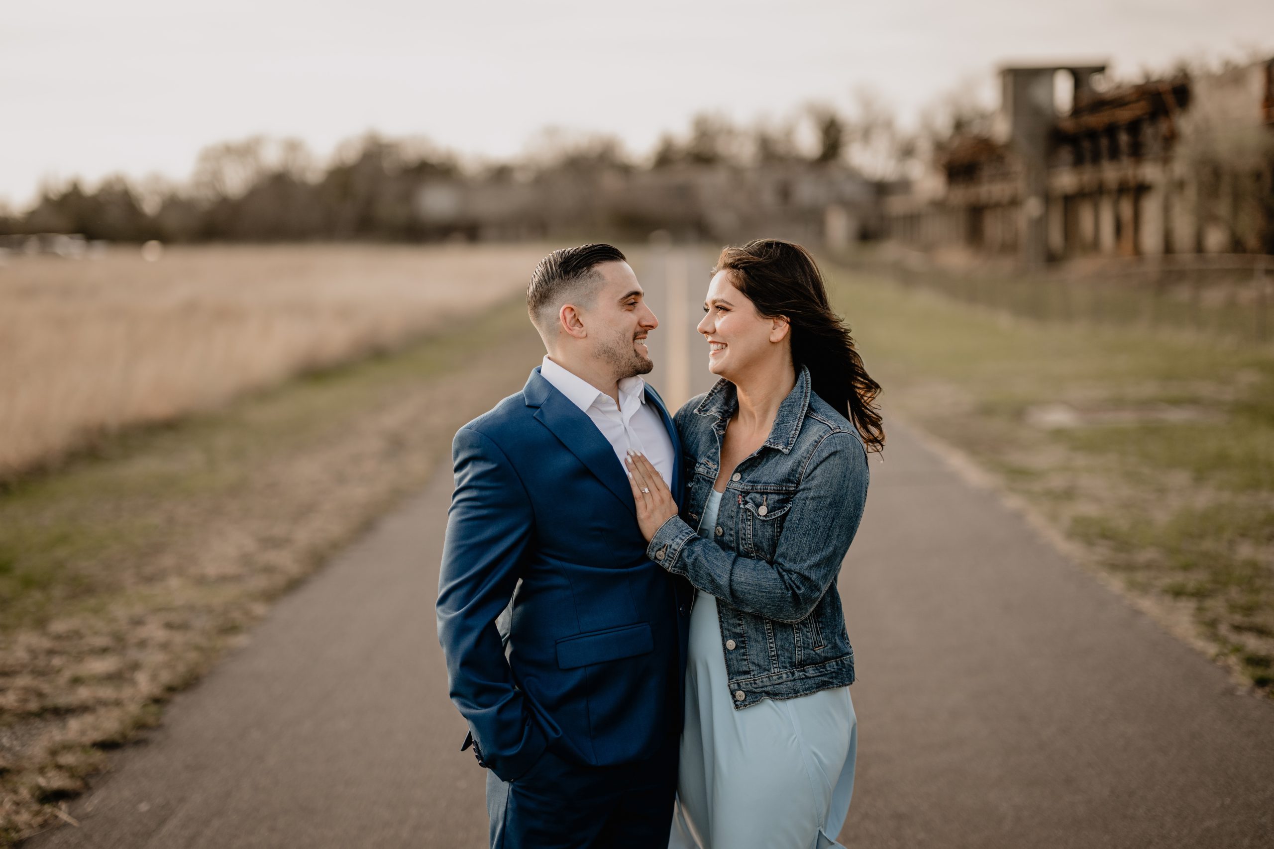 Couple standing smiling in the middle of the road on their engagement session at Sandy Hook Beach.