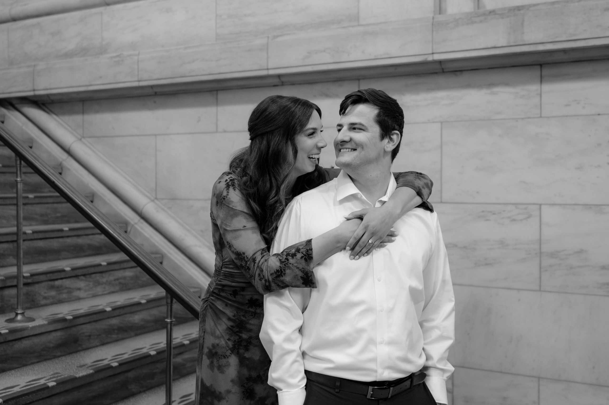 Couple hugging by the stairs at their Engagement Session at New York Public Library.